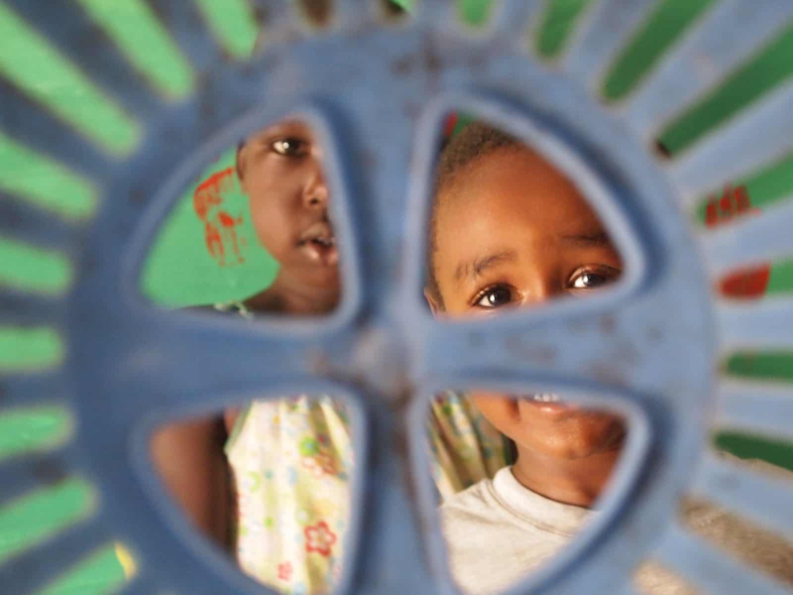 Two children look through a plastic structure.