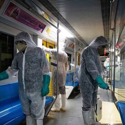 Three people in PPE disinfect the inside of a bus