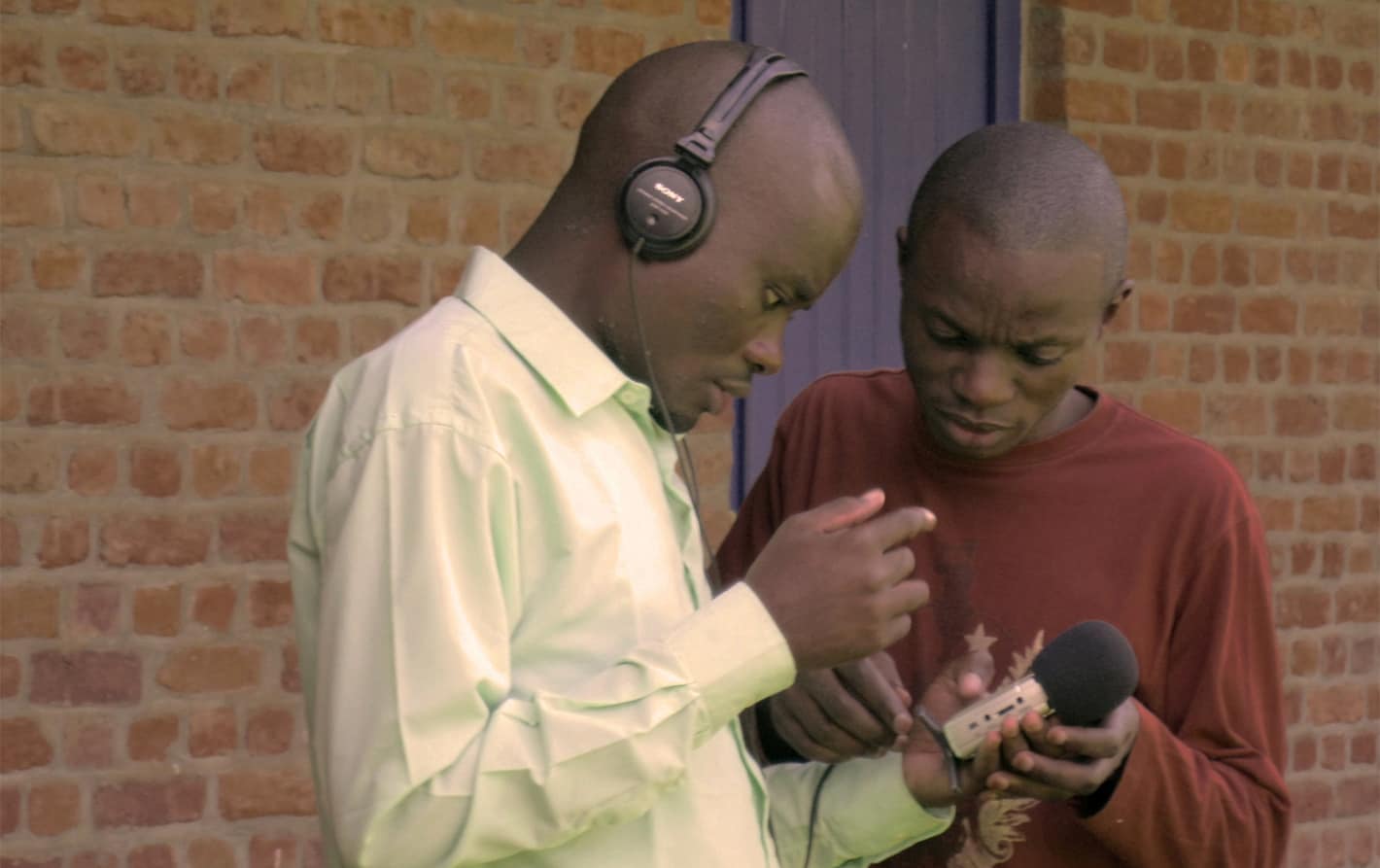 Two men look at an audio recorder.
