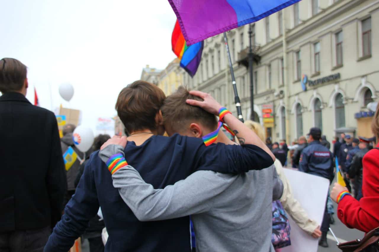 Two men hug at a gay pride parade.