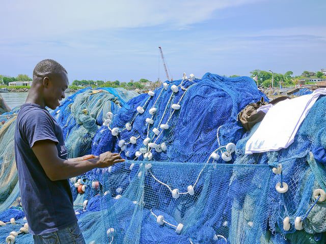 Man by pile of fishing nets.