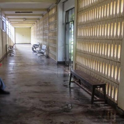 A man sits by himself in an empty hospital corridor.