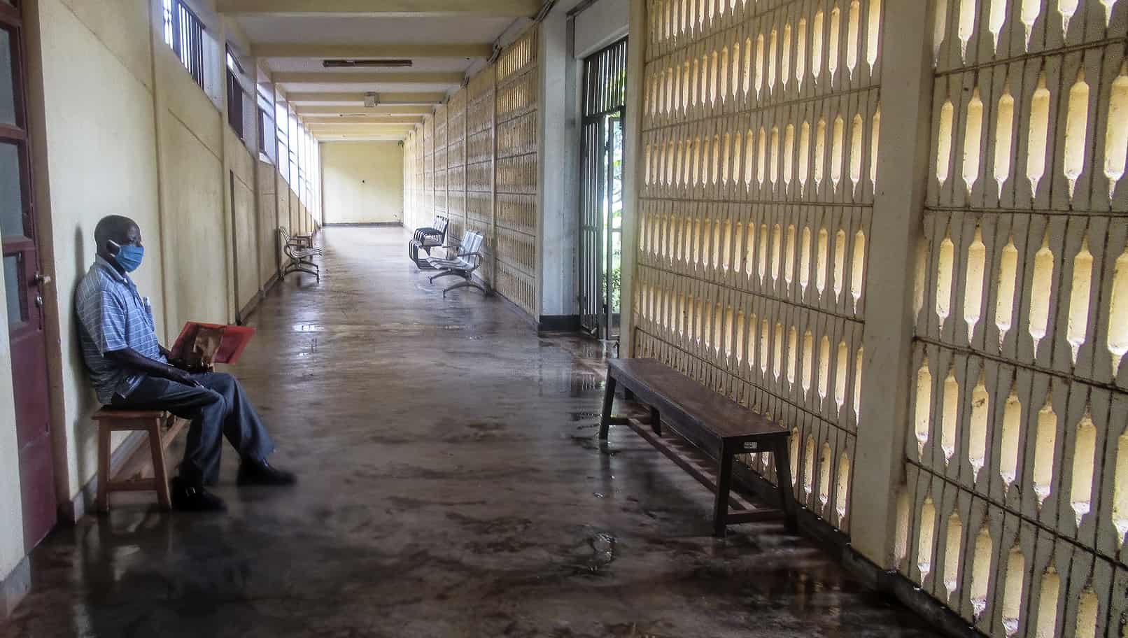 A man sits by himself in an empty hospital corridor.