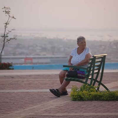 A woman sits by herself on a bench.