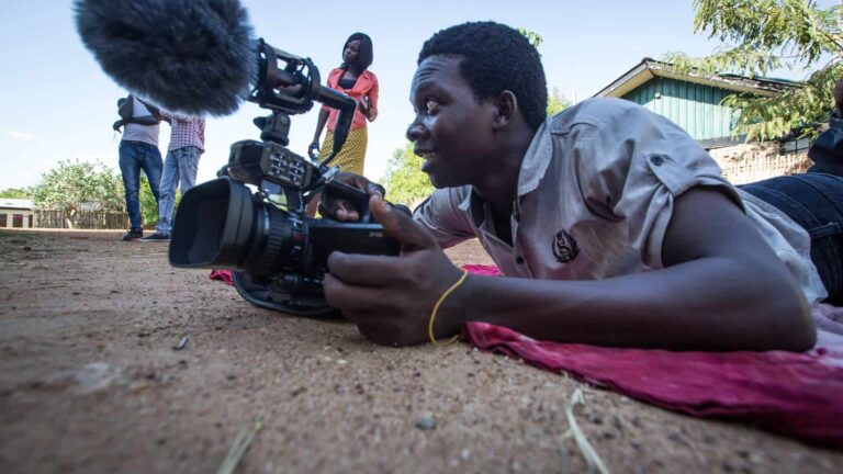 A man films, lying on the ground.