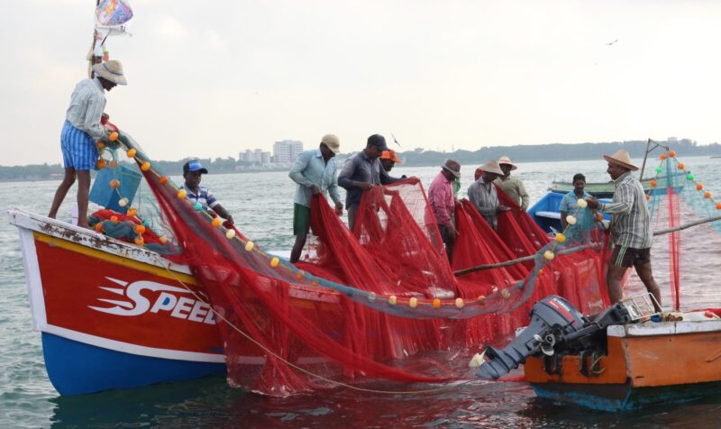 Men pull nets on to a fishing boat