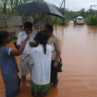 A group of people stand in deep water on a flooded street