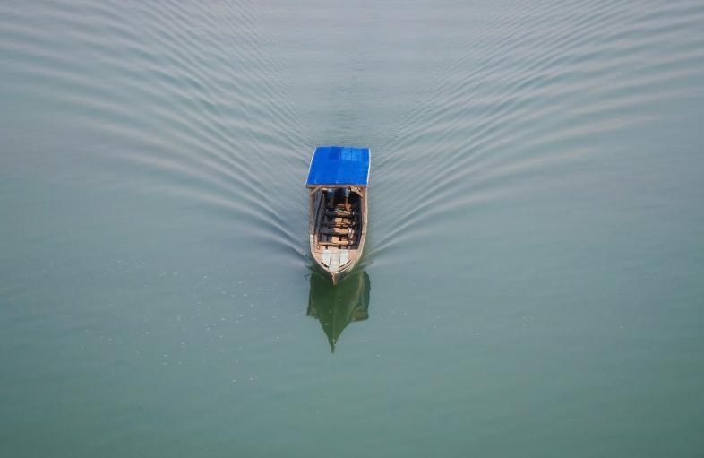 A small boat with a roof floats on the water.