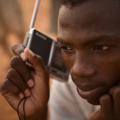 A man holds a portable radio up to his ear