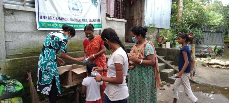 A group of women distribute supplies outside of a house