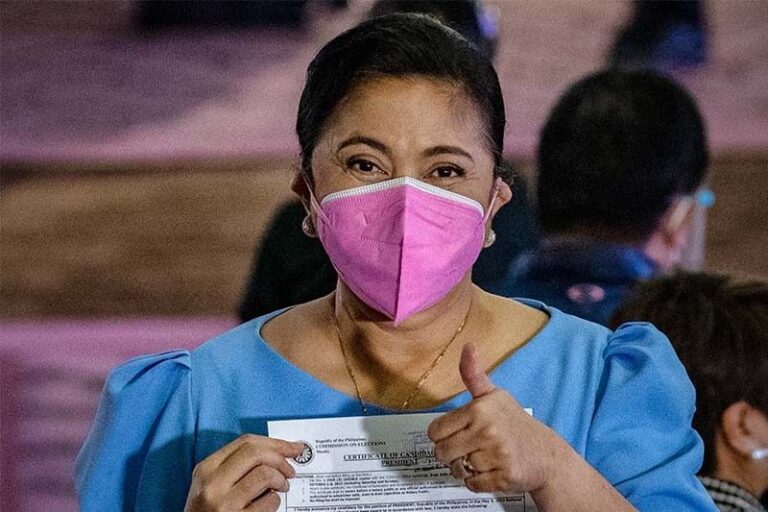 A woman wearing a face mask gives a thumbs up.