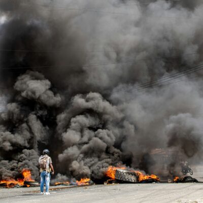 Reporter captures video in front of burning barricade in Haiti during protest.
